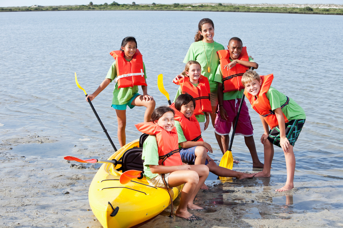 Summer camp counselor and children with kayak